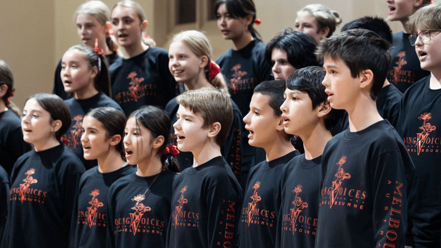 Young Voices of Melbourne Choir high school age children wearing black and red uniform singing and happy.